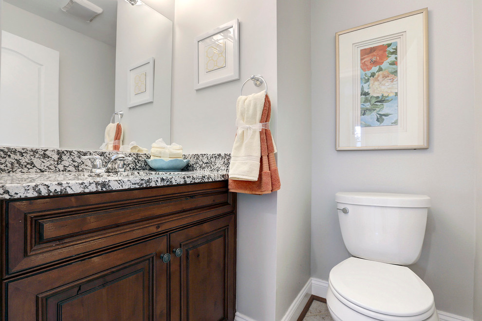 Small transitional powder room in DC Metro with an undermount sink, raised-panel cabinets, medium wood cabinets, granite benchtops, a two-piece toilet and ceramic floors.