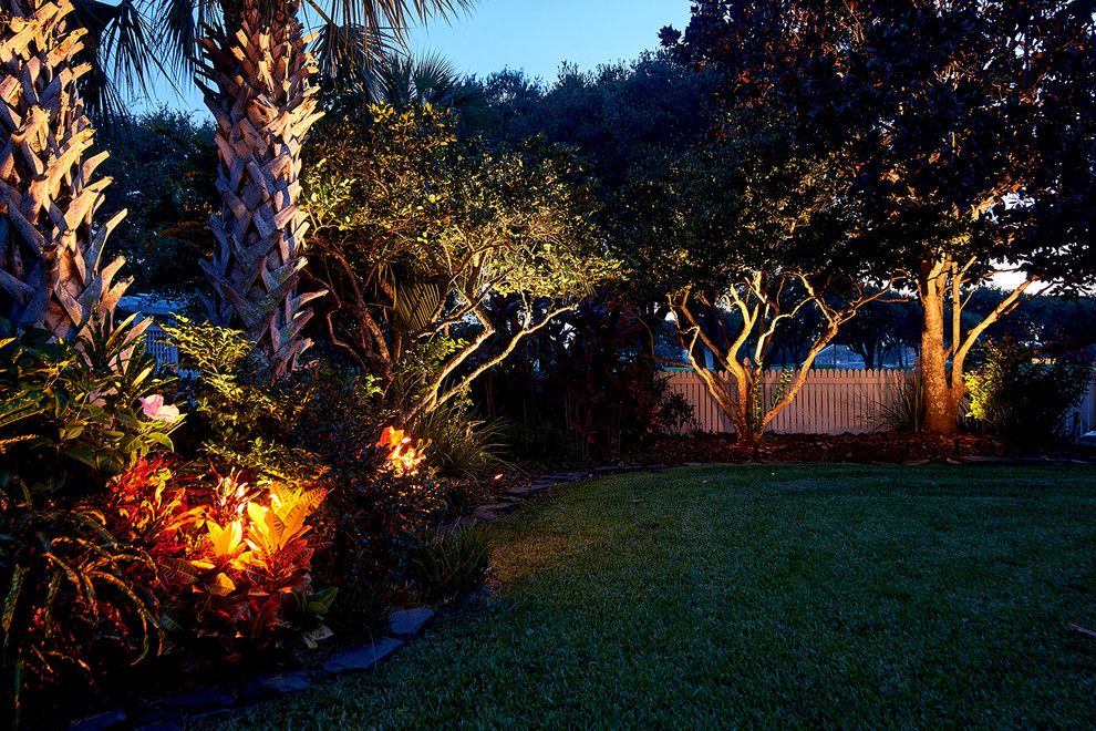This is an example of a mid-sized tropical backyard formal garden in Jacksonville with mulch.