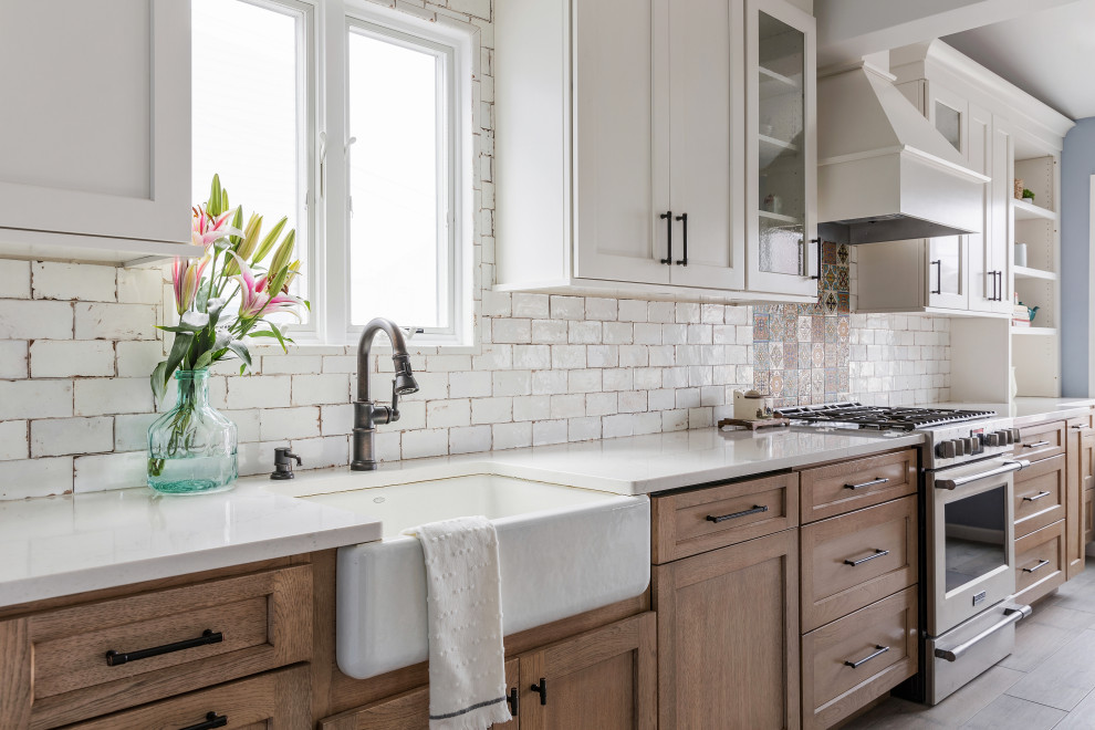 Inspiration for a mid-sized cottage galley gray floor and vaulted ceiling enclosed kitchen remodel in New York with a farmhouse sink, shaker cabinets, medium tone wood cabinets, quartz countertops, white backsplash, ceramic backsplash, stainless steel appliances, no island and white countertops