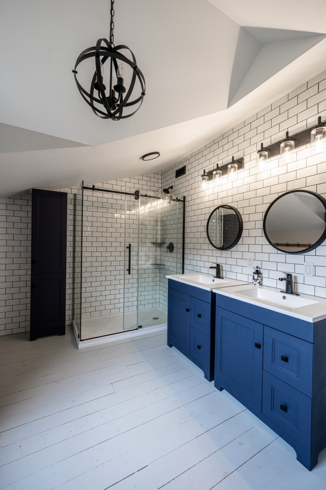 Свежая идея для дизайна: большая главная ванная комната в стиле кантри с фасадами в стиле шейкер, синими фасадами, отдельно стоящей ванной, угловым душем, раздельным унитазом, белой плиткой, плиткой кабанчик, серыми стенами, деревянным полом, монолитной раковиной, столешницей из искусственного камня, серым полом, душем с раздвижными дверями, белой столешницей, тумбой под одну раковину, напольной тумбой и сводчатым потолком - отличное фото интерьера