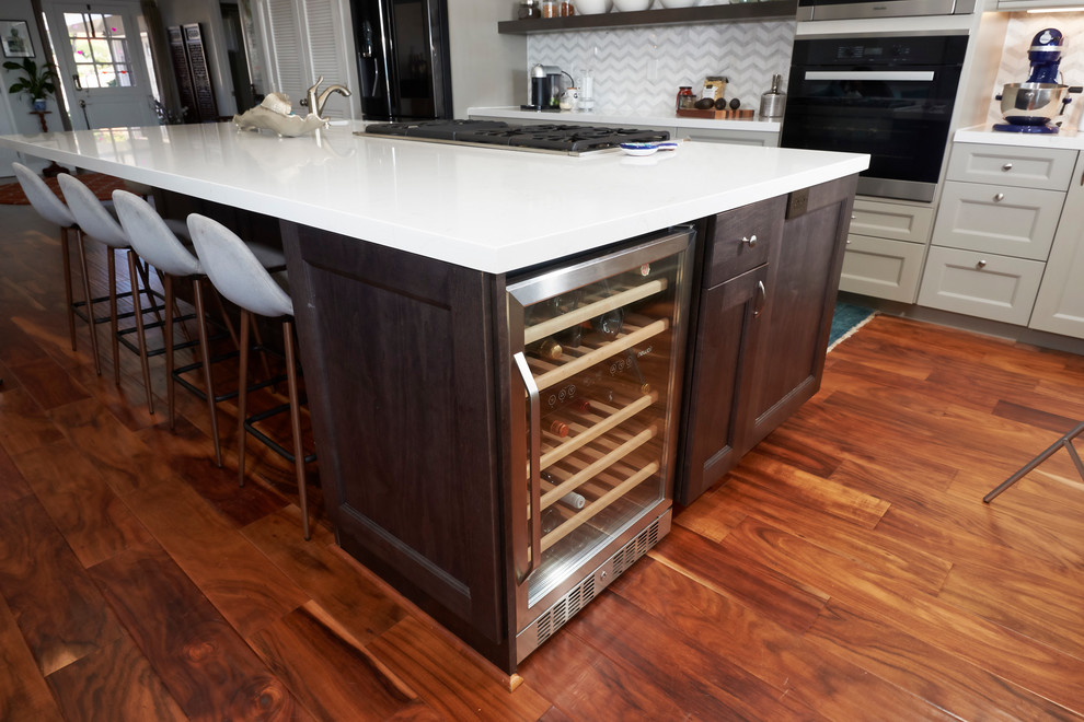 Large transitional l-shaped medium tone wood floor and brown floor open concept kitchen photo in Denver with an undermount sink, recessed-panel cabinets, gray cabinets, quartz countertops, white backsplash, marble backsplash, stainless steel appliances, an island and white countertops