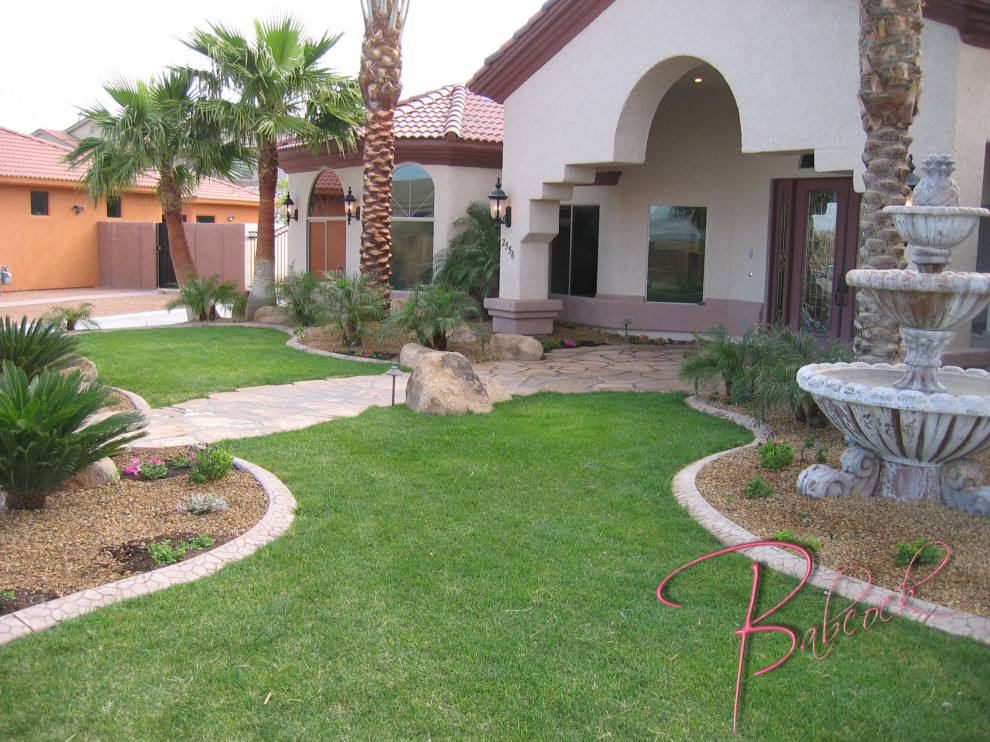 Modelo de jardín de secano exótico de tamaño medio en verano en patio delantero con paisajismo estilo desértico, exposición total al sol, adoquines de piedra natural y con piedra