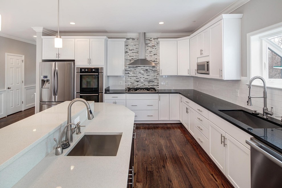 Inspiration for a transitional l-shaped open plan kitchen in DC Metro with an undermount sink, recessed-panel cabinets, white cabinets, solid surface benchtops, multi-coloured splashback, glass tile splashback, stainless steel appliances, dark hardwood floors and with island.
