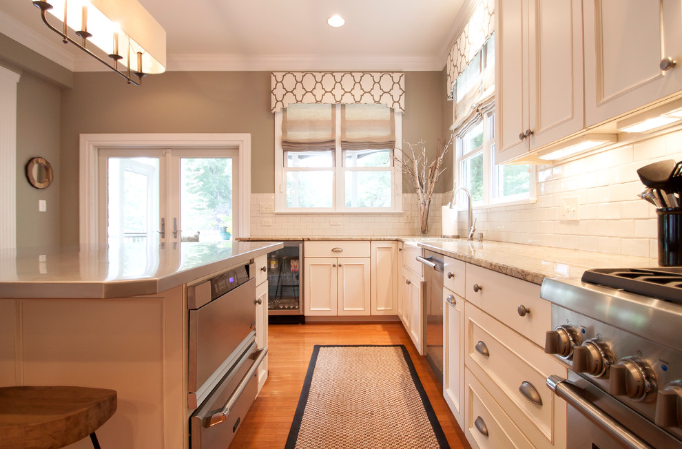Large transitional medium tone wood floor kitchen photo in DC Metro with an undermount sink, white cabinets, granite countertops, white backsplash, ceramic backsplash, stainless steel appliances and two islands