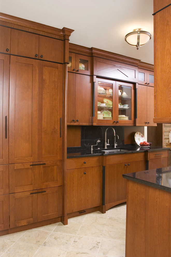 Photo of a mid-sized traditional galley separate kitchen in Chicago with an undermount sink, flat-panel cabinets, medium wood cabinets, solid surface benchtops, brown splashback, timber splashback, stainless steel appliances, limestone floors, no island and beige floor.