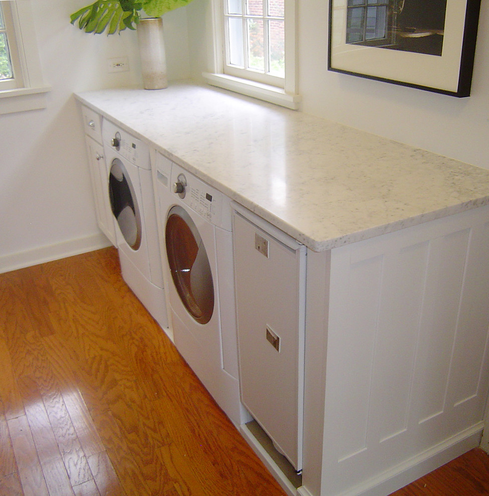 Inspiration for a mid-sized traditional galley dedicated laundry room in Philadelphia with recessed-panel cabinets, white cabinets, marble benchtops, white walls, medium hardwood floors and a side-by-side washer and dryer.