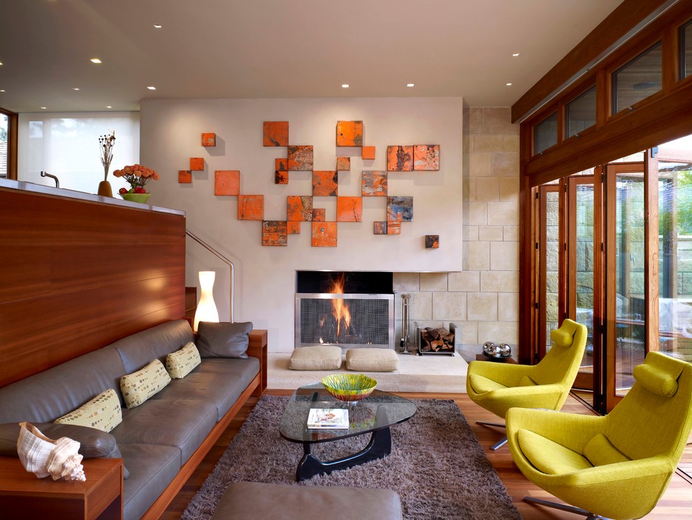 This is an example of a small midcentury open concept living room in San Francisco with beige walls, light hardwood floors, a standard fireplace, a stone fireplace surround and no tv.