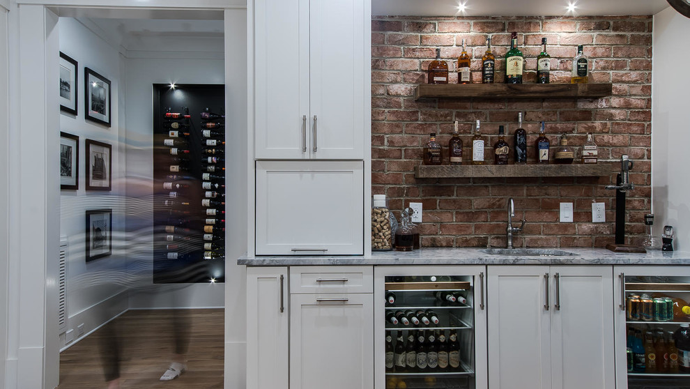 Mid-sized country wet bar in Raleigh with an undermount sink, shaker cabinets, white cabinets, marble benchtops, red splashback, brick splashback, light hardwood floors and beige floor.