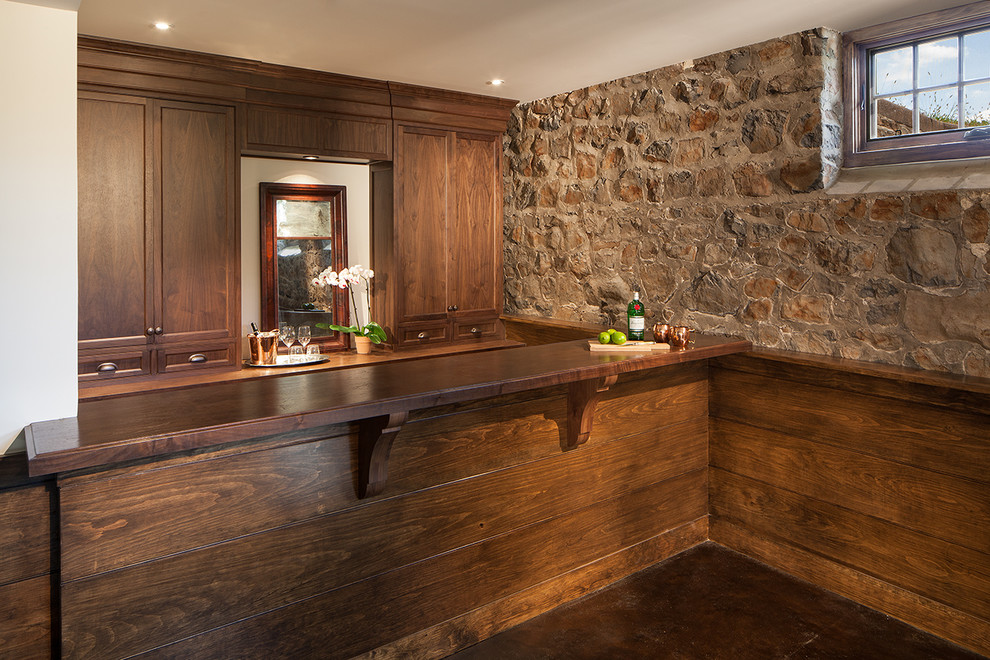 Mid-sized country galley wet bar in New York with recessed-panel cabinets, medium wood cabinets, wood benchtops, concrete floors, brown floor and brown benchtop.