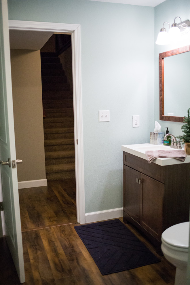 Inspiration for a mid-sized rustic 3/4 medium tone wood floor alcove bathtub remodel in St Louis with shaker cabinets, medium tone wood cabinets, a one-piece toilet, blue walls, an integrated sink and solid surface countertops