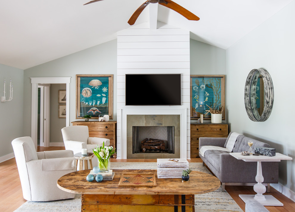 Design ideas for a mid-sized beach style living room in Jacksonville with medium hardwood floors, a standard fireplace, a stone fireplace surround and a wall-mounted tv.