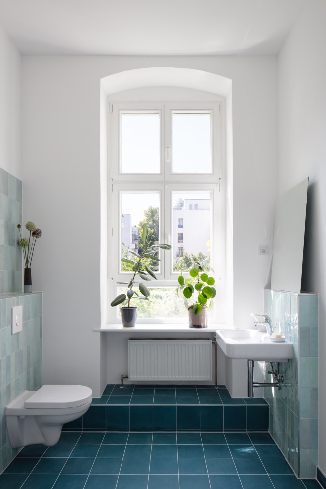 Пример оригинального дизайна: совмещенный санузел среднего размера в современном стиле с душем над ванной, раздельным унитазом, синей плиткой, керамической плиткой, синими стенами, полом из цементной плитки, душевой кабиной, подвесной раковиной, синим полом, открытым душем, тумбой под одну раковину и подвесной тумбой