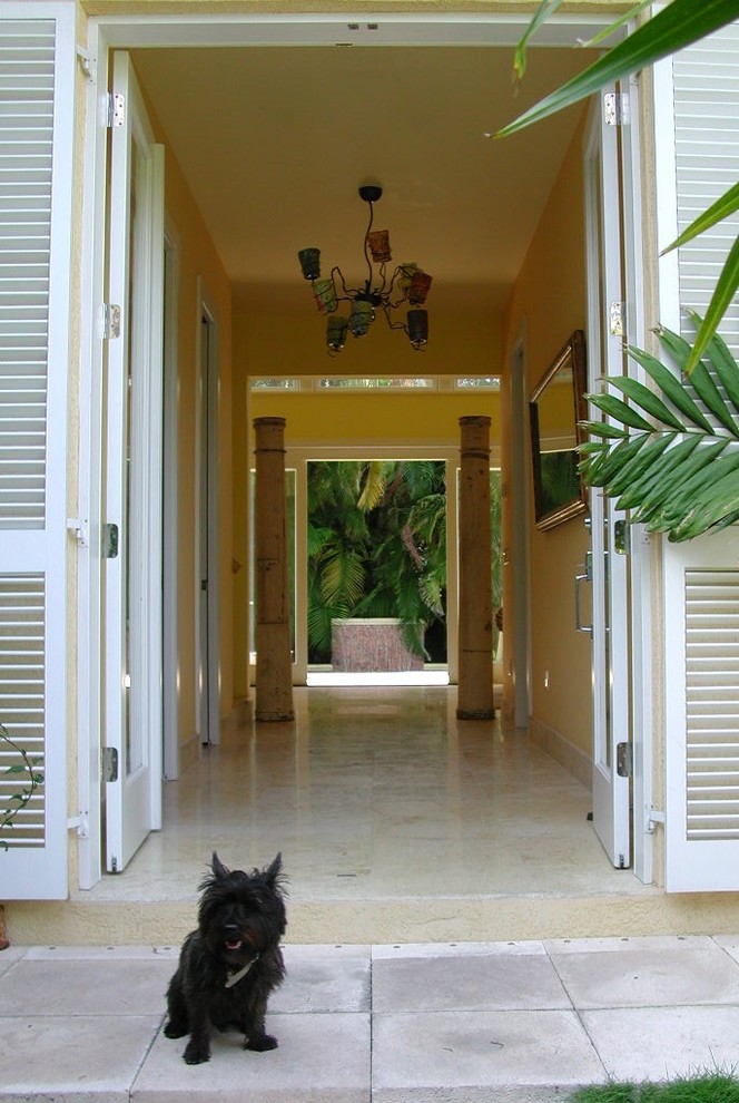 Design ideas for a mid-sized tropical front door in Miami with yellow walls, limestone floors, a double front door and a white front door.
