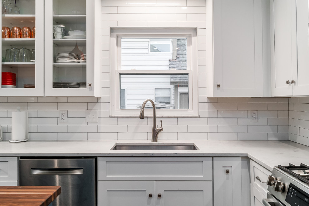 Inspiration for a mid-sized transitional l-shaped eat-in kitchen remodel in Columbus with shaker cabinets, quartz countertops, white backsplash, subway tile backsplash and an island