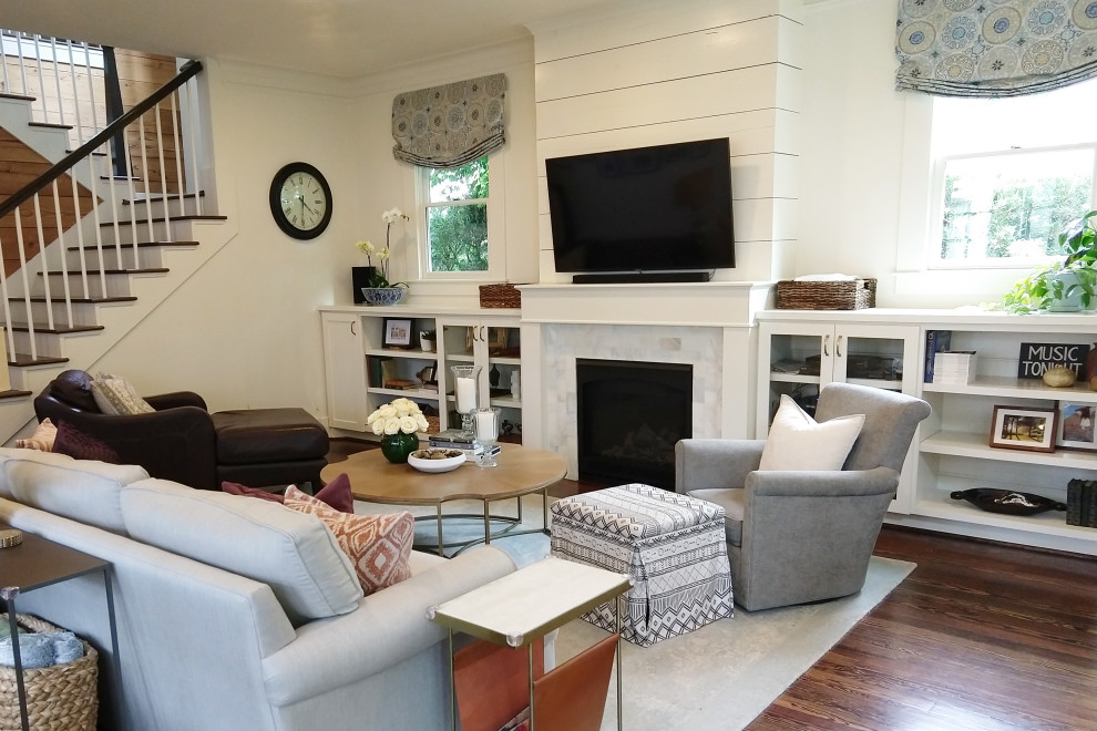 Cette photo montre un grand salon nature ouvert avec un mur blanc, un sol en bois brun, une cheminée standard, un manteau de cheminée en carrelage, un téléviseur fixé au mur et un sol marron.