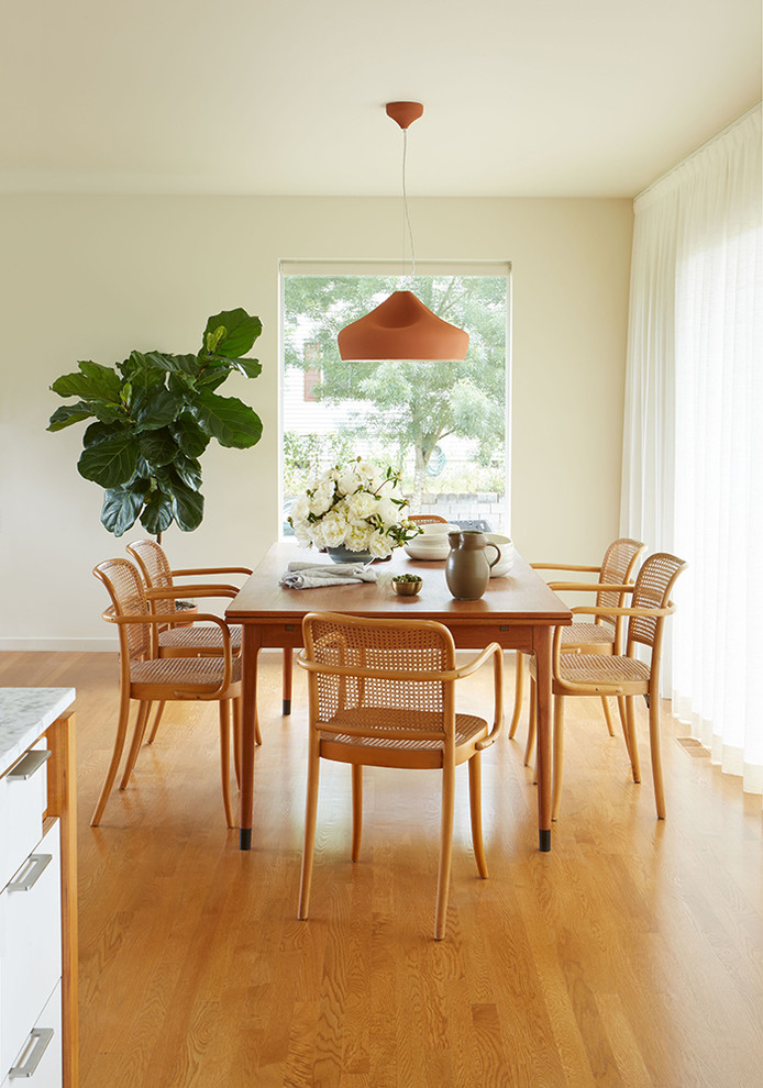 Inspiration for a mid-sized midcentury open plan dining in Seattle with white walls, medium hardwood floors, a standard fireplace, a brick fireplace surround and brown floor.