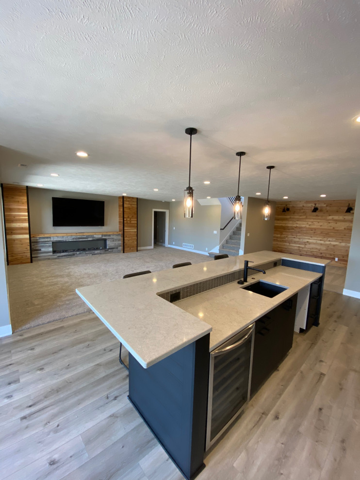 Example of a cottage vinyl floor, brown floor and wood wall basement design with gray walls, a standard fireplace and a stacked stone fireplace
