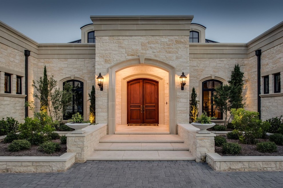 Inspiration for a large mediterranean two-storey beige house exterior with stone veneer, a hip roof and a metal roof.