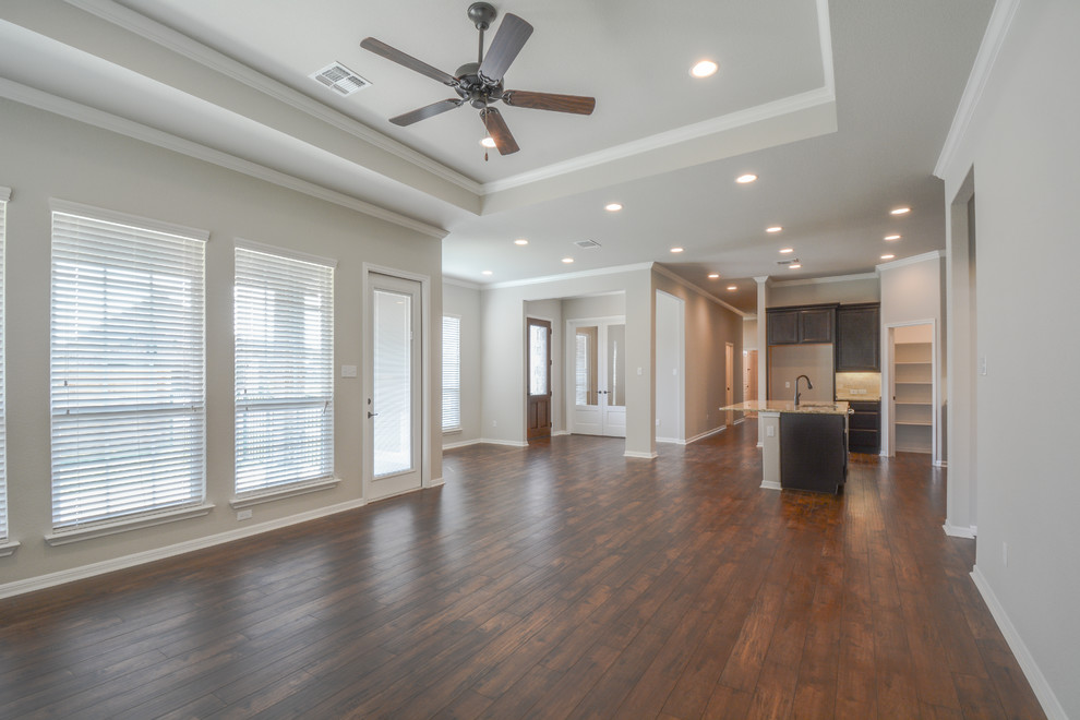 This is an example of a mid-sized arts and crafts open concept family room in Austin with beige walls, laminate floors, no fireplace, no tv and brown floor.