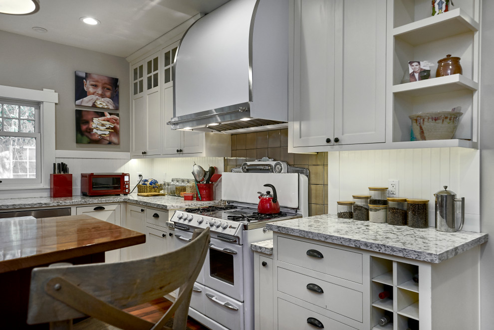 Mid-sized arts and crafts l-shaped kitchen in San Francisco with an undermount sink, shaker cabinets, white cabinets, granite benchtops, white splashback, timber splashback, white appliances, medium hardwood floors, with island, red floor and grey benchtop.