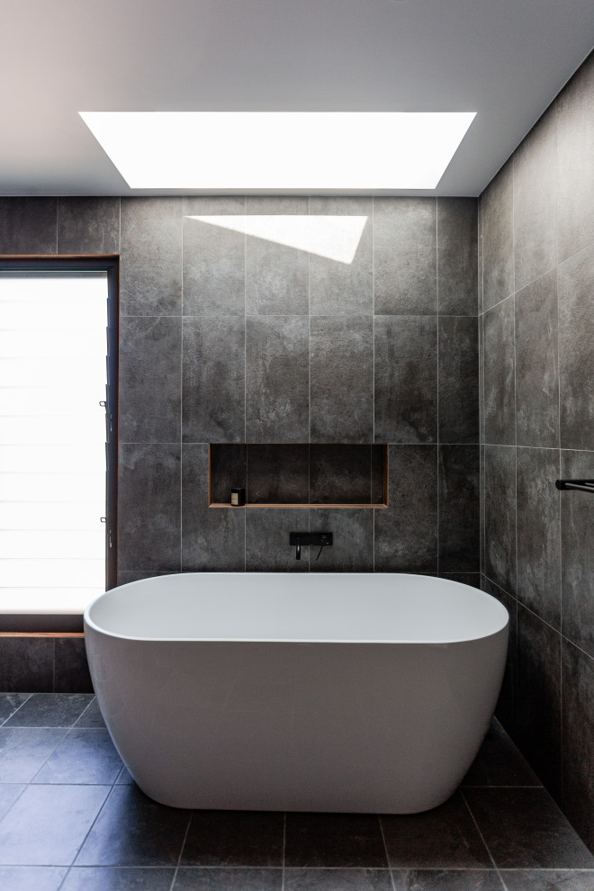 Design ideas for a mid-sized industrial bathroom in Central Coast with a freestanding tub, black walls, ceramic floors and black floor.