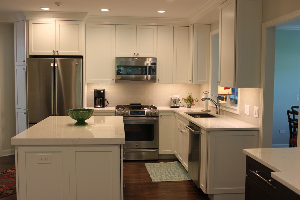 Enclosed kitchen - mid-sized transitional l-shaped dark wood floor and brown floor enclosed kitchen idea in Chicago with an undermount sink, recessed-panel cabinets, white cabinets, quartzite countertops, white backsplash, subway tile backsplash, stainless steel appliances and an island