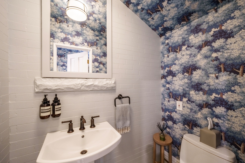 На фото: маленький туалет в классическом стиле с белыми фасадами, унитазом-моноблоком, синими стенами, раковиной с пьедесталом, напольной тумбой, потолком с обоями и кирпичными стенами для на участке и в саду