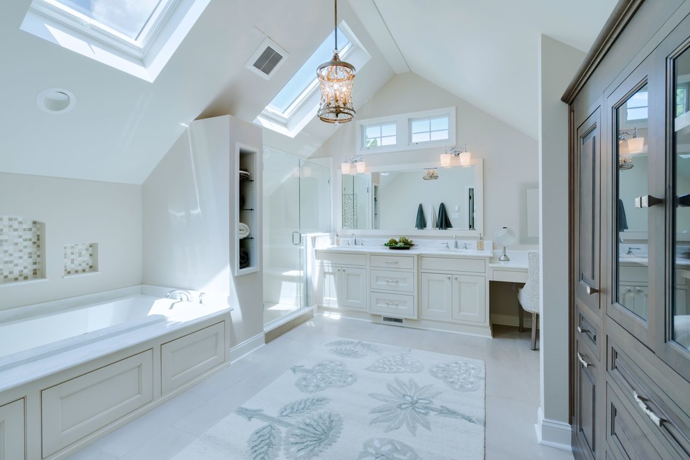This is an example of a large transitional master bathroom in Philadelphia with recessed-panel cabinets, white cabinets, a drop-in tub, a corner shower, a two-piece toilet, white tile, stone slab, white walls, ceramic floors, an undermount sink, quartzite benchtops, white floor and a hinged shower door.
