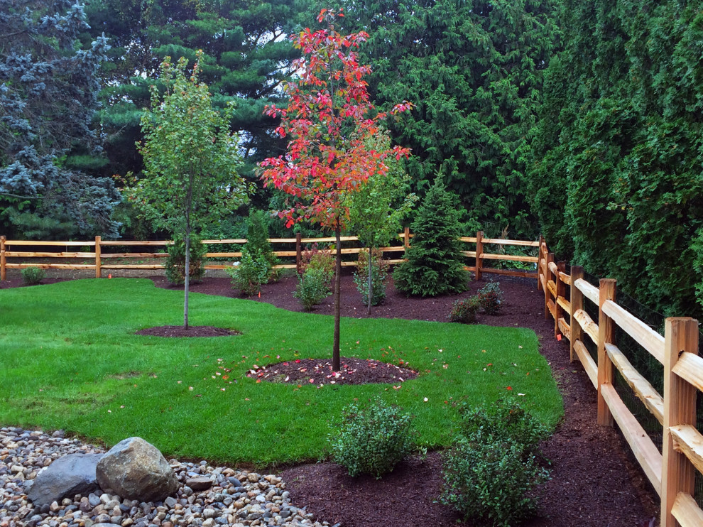 Photo of a medium sized traditional private partial sun garden for autumn in Providence with decorative stones and a wood fence.