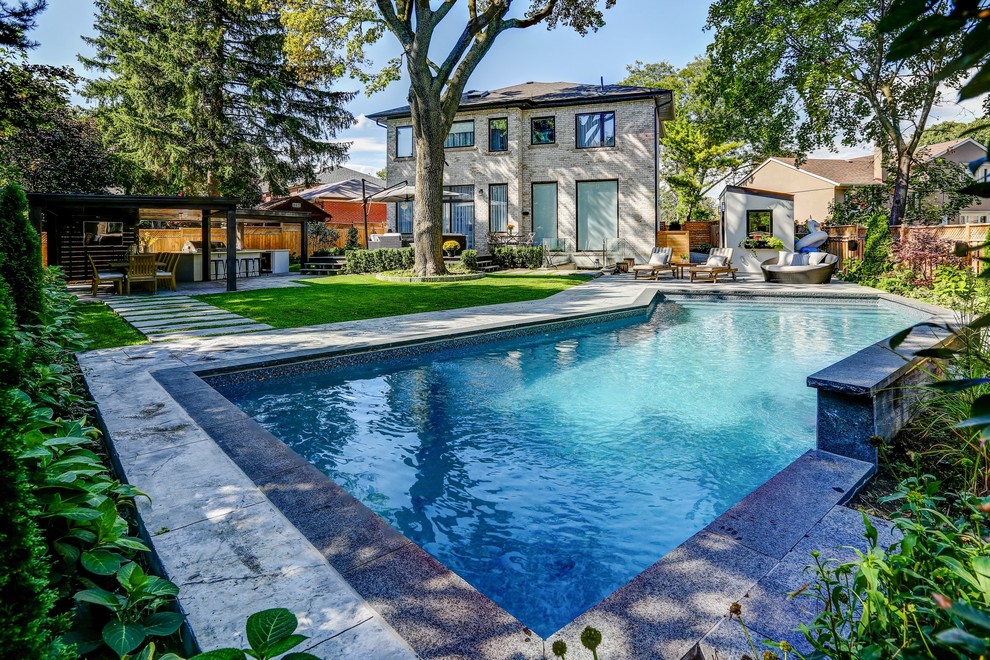 Design ideas for a mid-sized transitional backyard rectangular pool in Toronto with a pool house and stamped concrete.