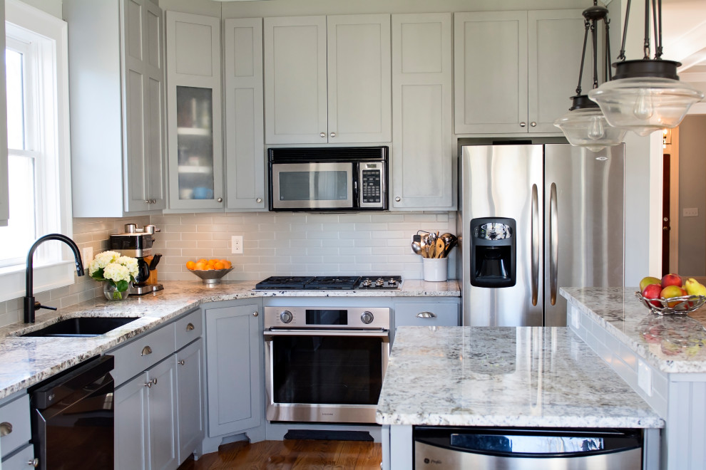 Inspiration for a medium tone wood floor kitchen remodel with an undermount sink, shaker cabinets, gray cabinets, granite countertops, gray backsplash, subway tile backsplash, stainless steel appliances and an island