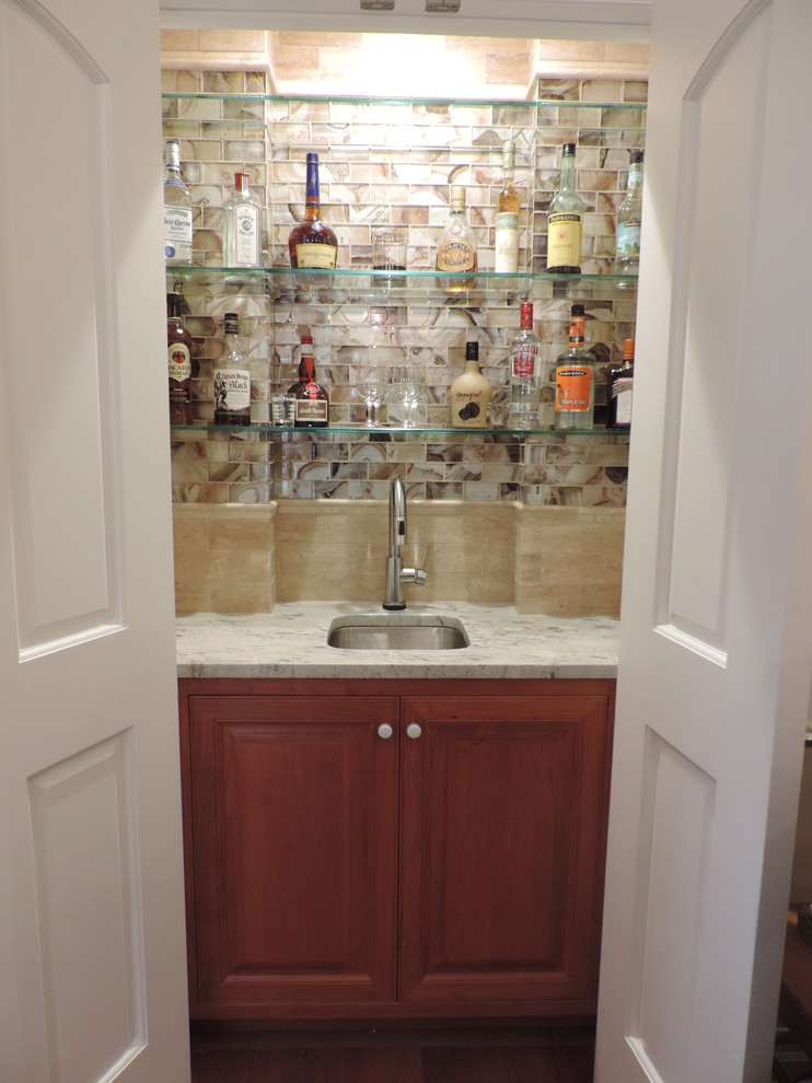 Photo of a small traditional home bar in Kansas City with beaded inset cabinets and orange cabinets.