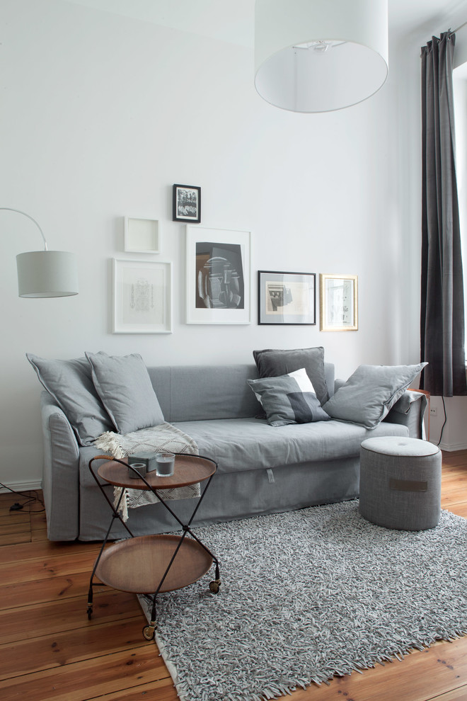 Inspiration for a small scandinavian loft-style family room in Berlin with white walls, laminate floors, no fireplace, no tv and brown floor.