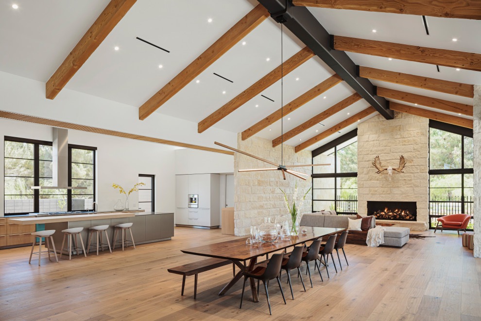 Offenes Modernes Esszimmer mit hellem Holzboden, Kamin, Kaminumrandung aus Stein, freigelegten Dachbalken und Ziegelwänden in Phoenix