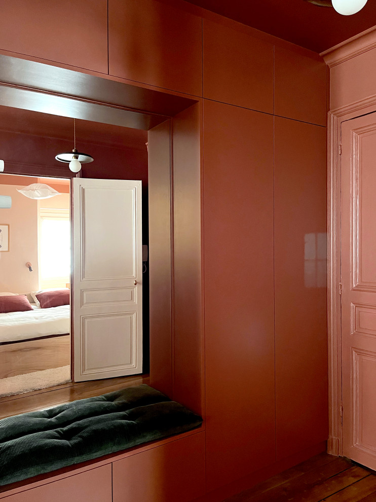 This is an example of a small traditional foyer in Paris with red walls, light hardwood floors, a red front door, brown floor and decorative wall panelling.