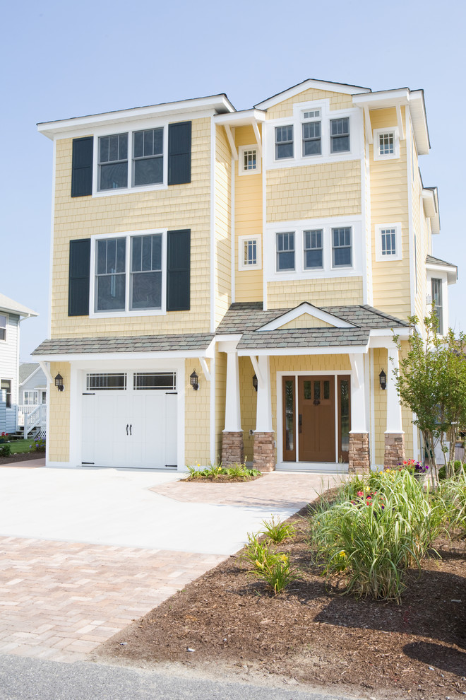 Photo of a large beach style three-storey yellow house exterior in Other with vinyl siding, a hip roof and a mixed roof.