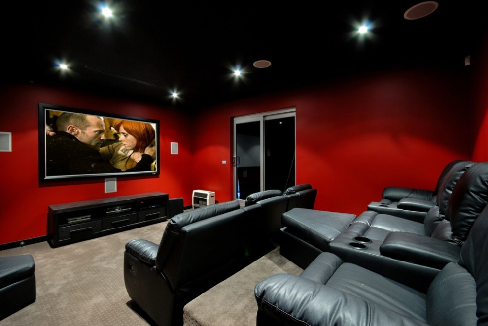 Cette photo montre une salle de cinéma tendance de taille moyenne et fermée avec un mur rouge, moquette, un téléviseur fixé au mur et un sol noir.