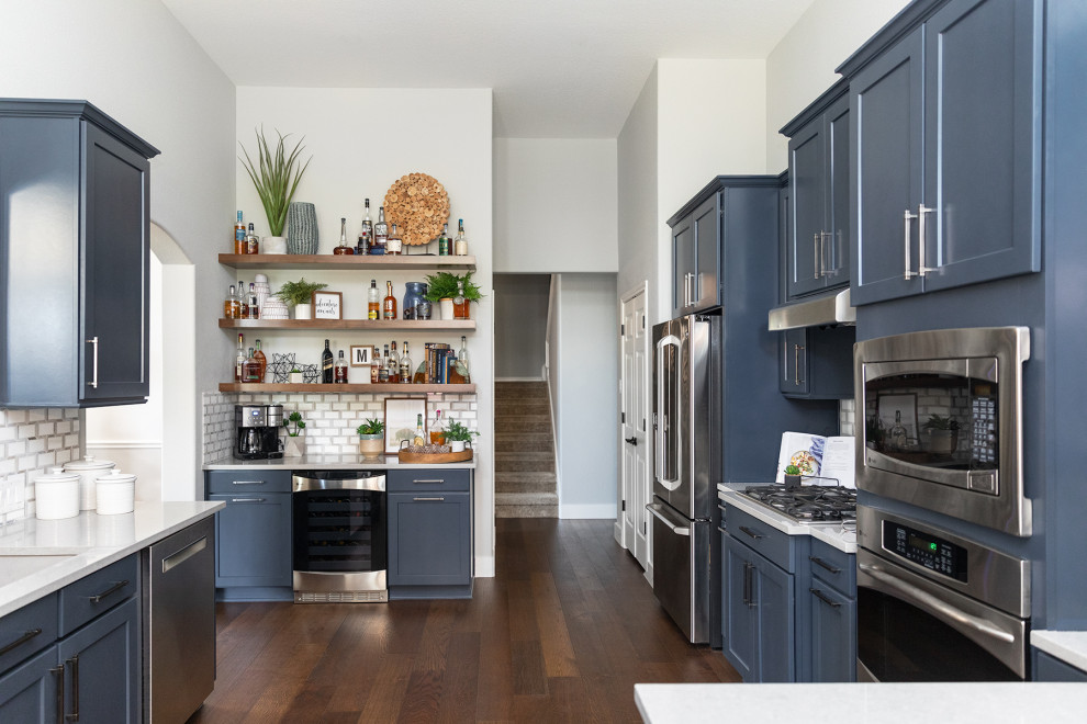 Imagen de cocina rústica sin isla con puertas de armario azules, salpicadero con mosaicos de azulejos y electrodomésticos de acero inoxidable