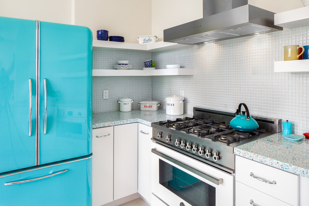 This is an example of a small eclectic u-shaped eat-in kitchen in San Francisco with a farmhouse sink, flat-panel cabinets, white cabinets, recycled glass benchtops, blue splashback, glass sheet splashback and porcelain floors.