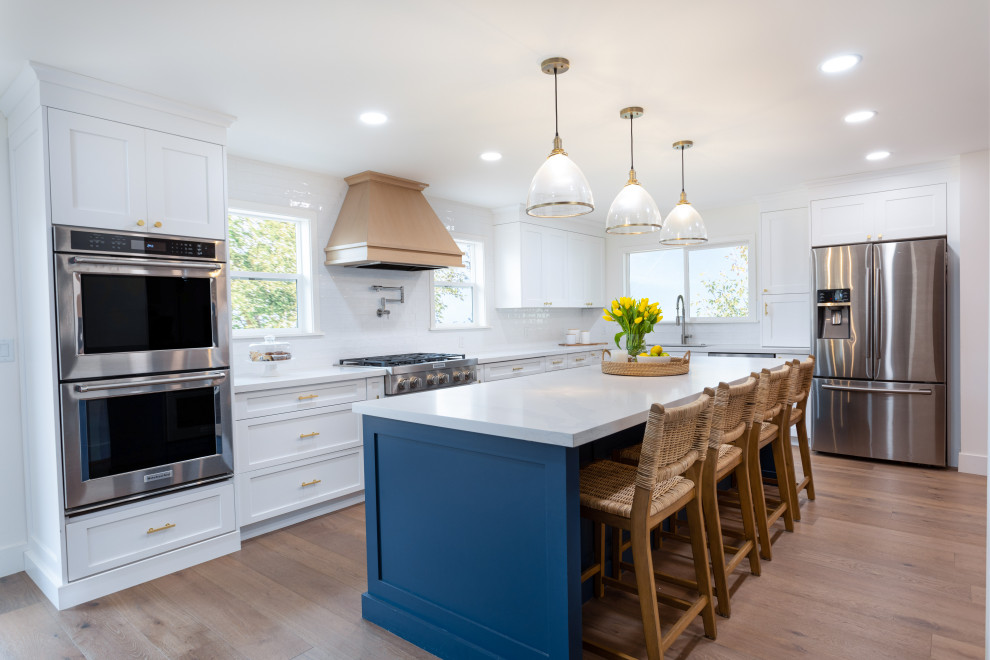 Inspiration for a country l-shaped kitchen/diner in Phoenix with a submerged sink, shaker cabinets, white cabinets, engineered stone countertops, white splashback, porcelain splashback, stainless steel appliances, an island and white worktops.