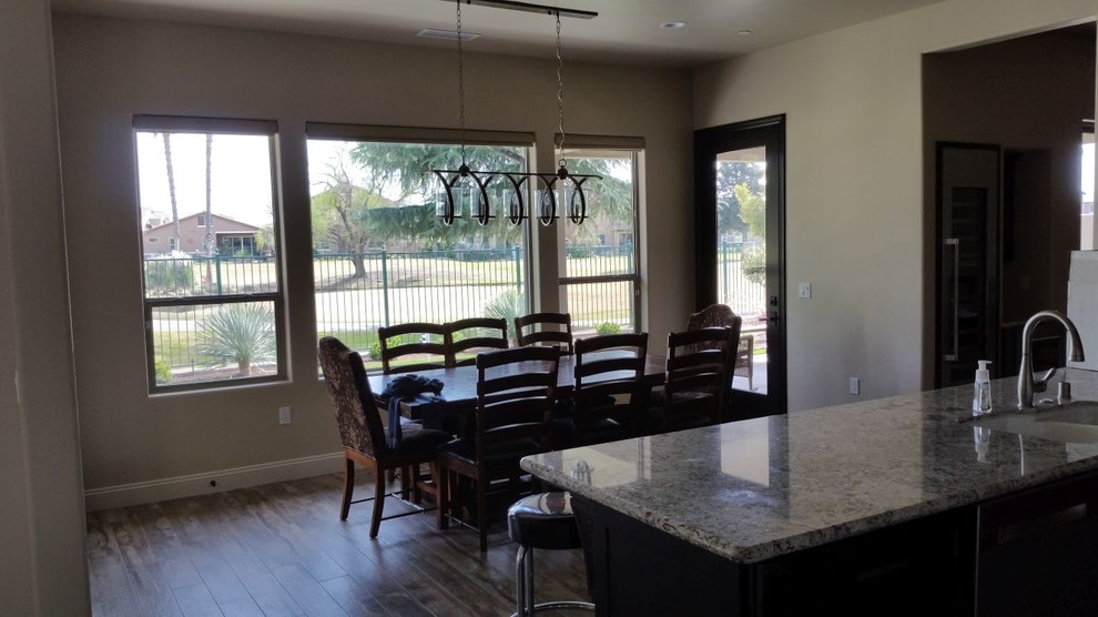 Open concept kitchen - large transitional u-shaped brown floor open concept kitchen idea with an undermount sink, recessed-panel cabinets, dark wood cabinets, granite countertops, beige backsplash, porcelain backsplash, stainless steel appliances and an island