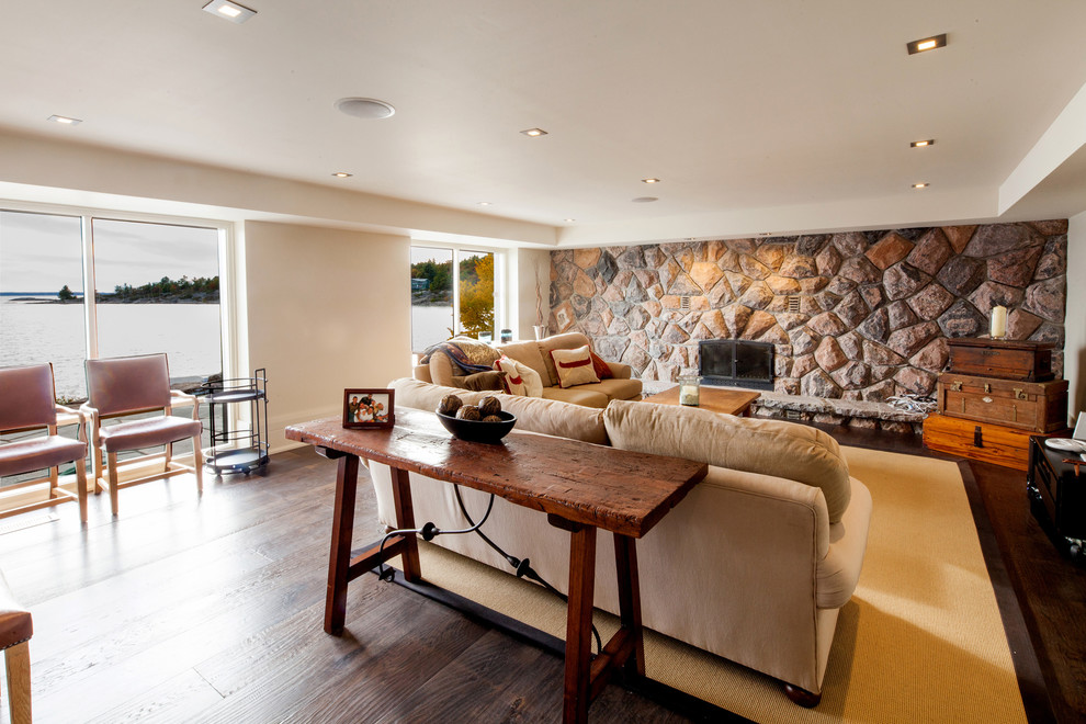 Mid-sized country enclosed family room in Toronto with a game room, white walls, dark hardwood floors, a standard fireplace, a stone fireplace surround, a wall-mounted tv and brown floor.