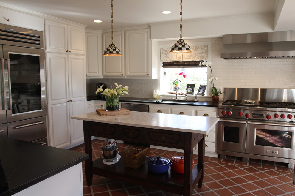 Photo of a traditional kitchen in Los Angeles with an undermount sink, soapstone benchtops, white splashback, subway tile splashback, stainless steel appliances, terra-cotta floors and with island.