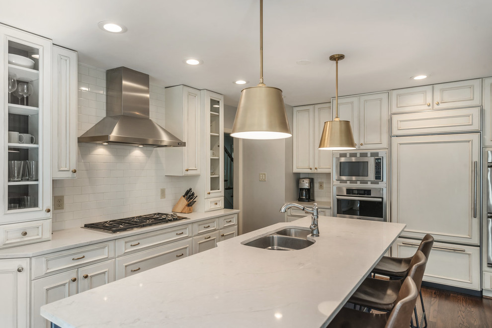 Kitchen - transitional medium tone wood floor and brown floor kitchen idea in DC Metro with an undermount sink, recessed-panel cabinets, white cabinets, granite countertops, white backsplash, subway tile backsplash, stainless steel appliances, an island and white countertops