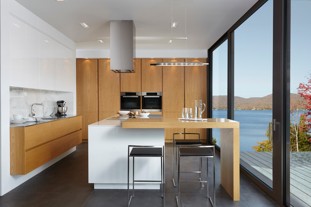 Design ideas for a contemporary kitchen in Montreal with an undermount sink, flat-panel cabinets, medium wood cabinets, stainless steel benchtops, white splashback, stainless steel appliances and with island.