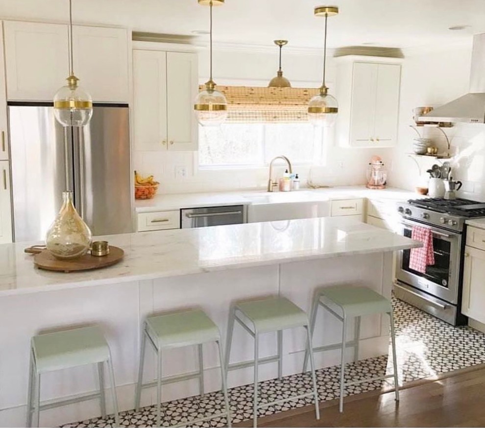 This is an example of a large transitional kitchen in Atlanta with shaker cabinets, white cabinets, stainless steel appliances, with island, a farmhouse sink, quartzite benchtops, multi-coloured splashback, cement tile splashback, medium hardwood floors and brown floor.