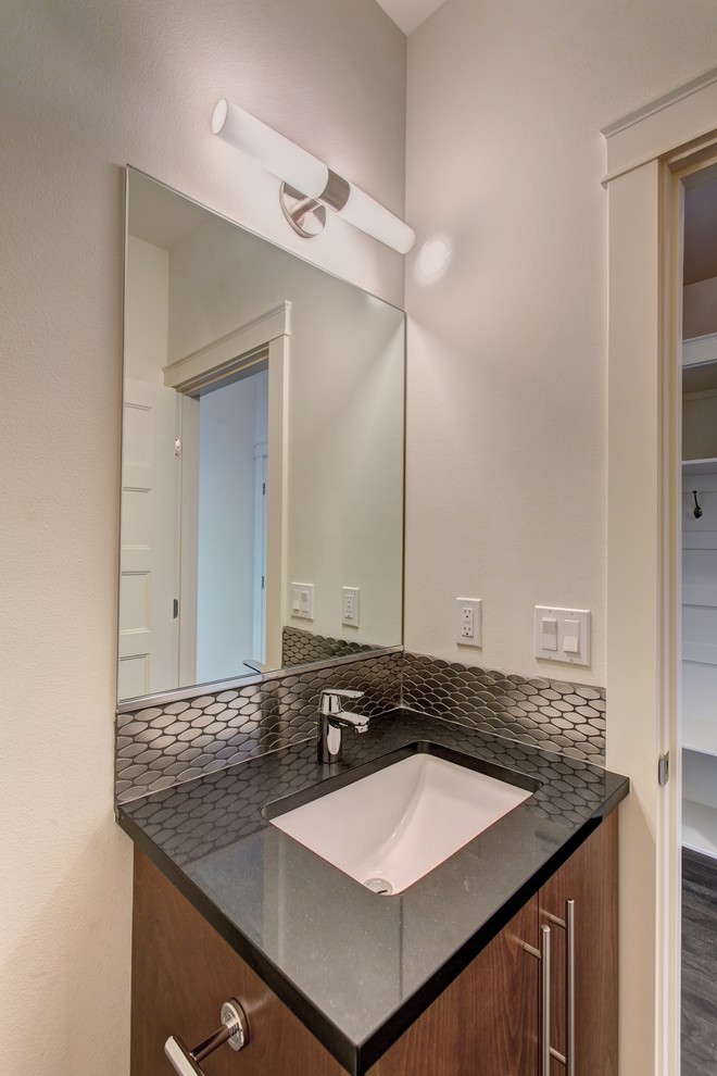 Small modern bathroom in Seattle with flat-panel cabinets, light wood cabinets, an alcove tub, a two-piece toilet, black tile, metal tile, white walls, porcelain floors, an undermount sink, engineered quartz benchtops and grey floor.