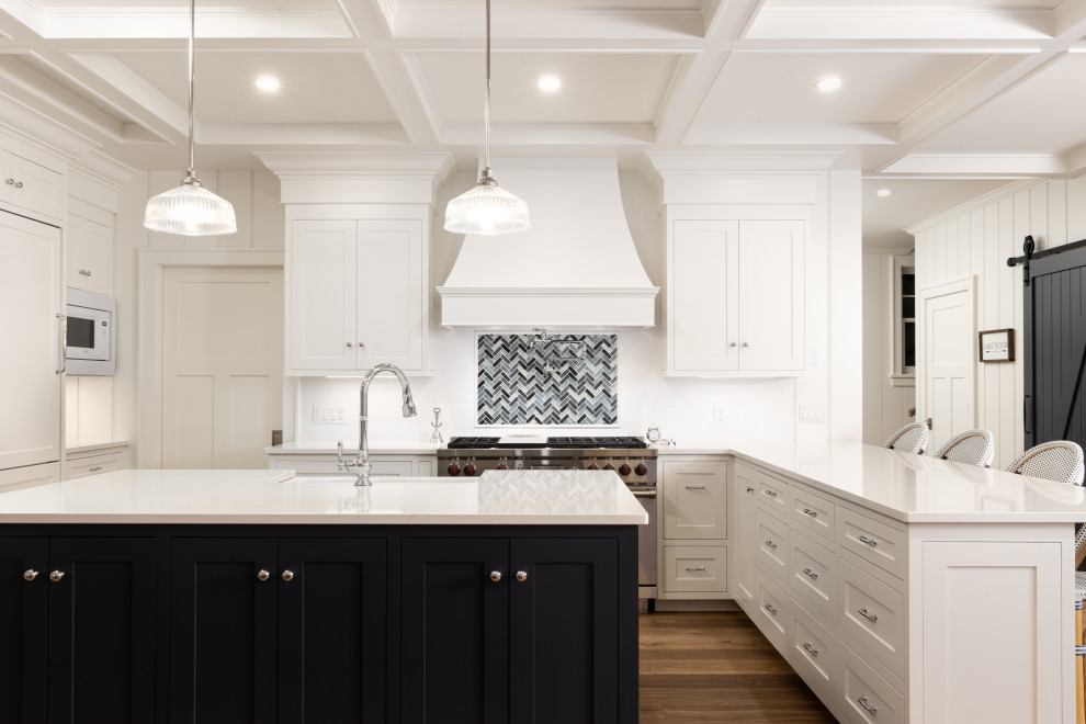 Design ideas for a beach style u-shaped kitchen in Other with a farmhouse sink, shaker cabinets, white cabinets, white splashback, stainless steel appliances, medium hardwood floors, with island, brown floor, white benchtop and coffered.
