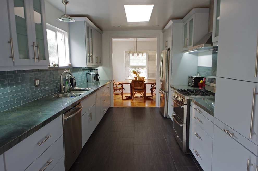 This is an example of a mid-sized contemporary galley eat-in kitchen in Los Angeles with a double-bowl sink, shaker cabinets, white cabinets, blue splashback, glass tile splashback, stainless steel appliances, porcelain floors, granite benchtops and no island.