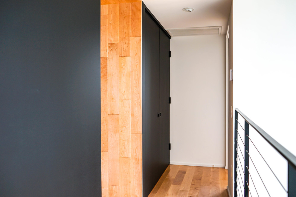 Mid-sized modern hallway in Los Angeles with black walls, light hardwood floors and brown floor.